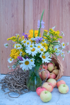 chamomiles and yellow and blue wild flowers bouquet with applesの写真素材