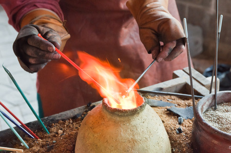 Glass artist in his workshop  making glass beads in traditional style の写真素材