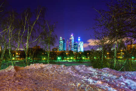 Moscow city skyscrapers by the winter night. View from the river throw birch trees.の写真素材