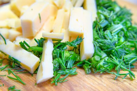 cheese and dill chopped on a wooden boardの写真素材