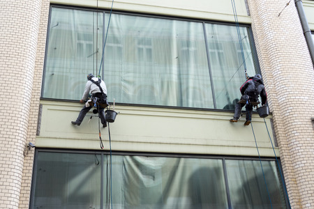 Two men cleaning windows service on high rise buildingの写真素材