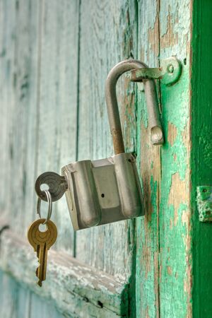 Old rusty padlock with two keys on a wooden doorの写真素材