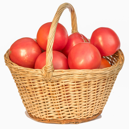 Fresh red tomatoes in a basket on a white backgroundの写真素材