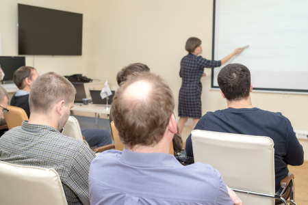 adult students learning - rear view of people and teacher near the deskの写真素材
