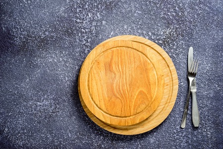 Wooden round cutting boards with empty space, fork and knife on a table.の写真素材