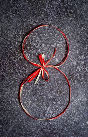 Red and white gift celebration ribbon in 8 digit shape on rustic grey background. Happy woman's dayの写真素材