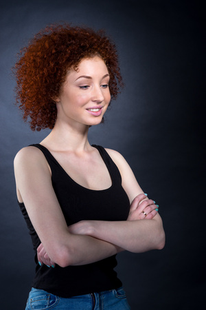 portrait of red-haired girl looking down with her hands crossed on her chestの写真素材