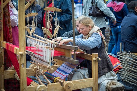 Moscow, Russia - September 11, 2016: Moscow City Day, 869 anniversary of the city. Performance on Tverskaya Street. Two girls in vintage dresses woven fabric on a loom.のeditorial素材