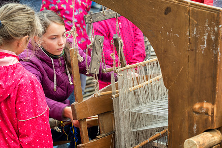 Moscow, Russia - September 11, 2016: Moscow City Day, 869 anniversary of the city. Performance on Tverskaya Street. Two girls in vintage dresses woven fabric on a loom.のeditorial素材