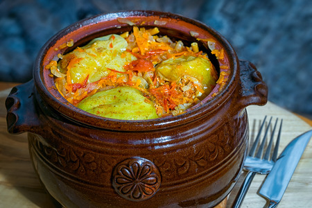 clay pot with baked stuffed peppers on the tableの写真素材