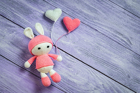 Handmade crochet rabbit toy with two heart balls. Amigurumi doll, space for text.