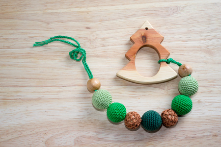 Necklace made from knitted beads and toys for the baby sitting in a sling. Wooden Christmas tree on...