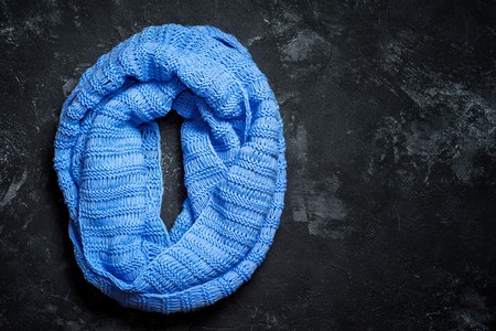 Blue knitted wool circle scarf on a black background with copy spaceの写真素材