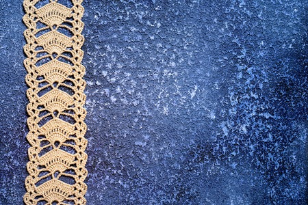 Beige crochet lace on a beautiful grunge textural dark blue cement background. Excellent background...