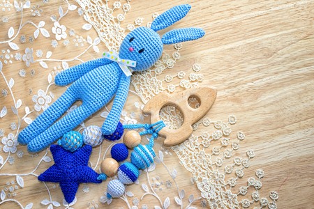 Handmade crochet rabbit toy and spaceship sling beads on a wooden background and lace with copy spaceの写真素材