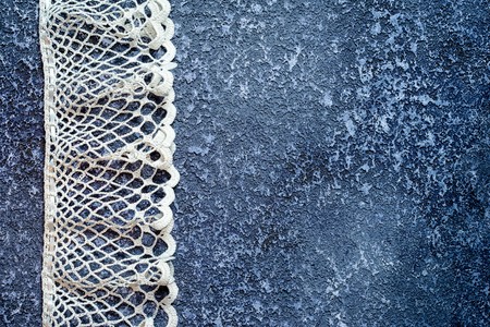 White crochet lace on a beautiful grunge textural dark cement background. Excellent background for the blog of needleworkの写真素材