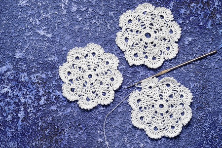 three crochet doily and hook on a cement blue background, copy space. suitable for needlework blog backgroundの写真素材