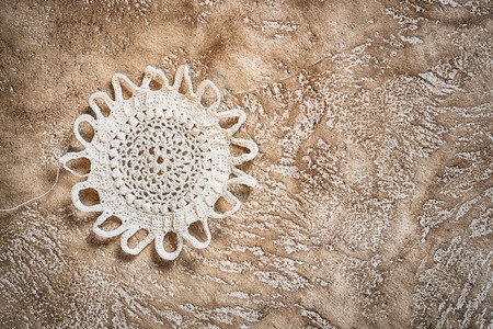 white crocheted handmade doily in a shape of the sun with copy space on a cement background, suitable as the art background for your needlework blogの写真素材