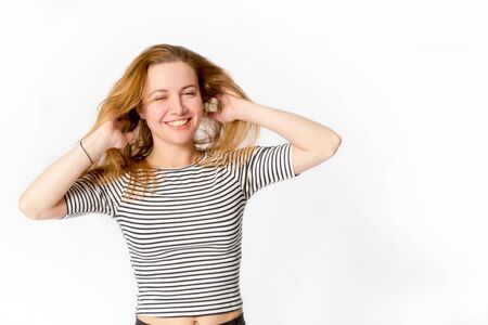 Smiling beautiful caucasian girl with her hands touching hairの写真素材