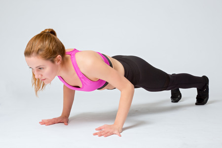 Young woman exercising - doing a plank in a studio