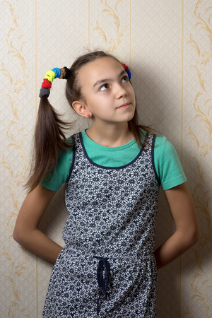 11 year old girl is leaning against the wall and looks up dreamilyの写真素材