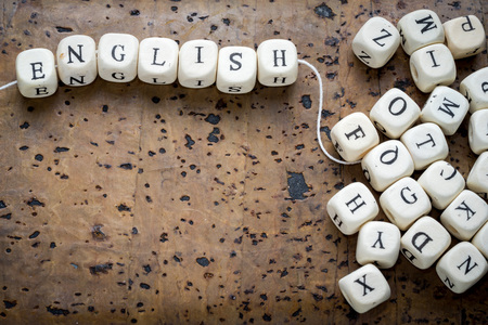 English text on a wooden cubes strung on a thread on a brown cork background, copy spaceの写真素材