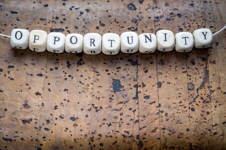 Opportunity text on a wooden cubes strung on a thread on a brown cork backgroundの写真素材