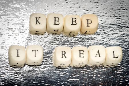 Keep it real text on a wooden cubes on a shiny silver backgroundの写真素材