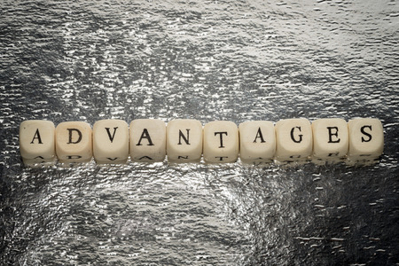 Advantages word on a wooden cubes on a shiny silver foil backgroundの写真素材
