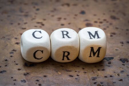 CRM (Customer Relationship Management) text on wooden cubes on a brown cork backgroundの写真素材