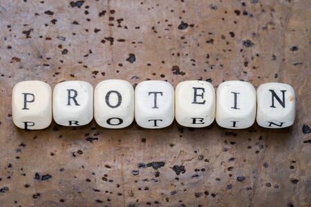 Protein word on wooden cubes on a brown cork backgroundの写真素材