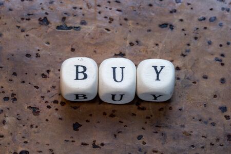 Buy text on a wooden cubes on a brown cork backgroundの写真素材