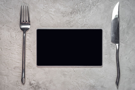 top view of a tablet with blank black screen with fork and knife and lots of copy space for your techno menu text, conceptの写真素材