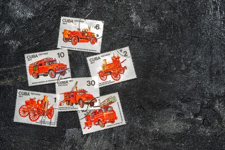 Moscow, Russia - April 20, 2017: Set of randomly lying postage stamps printed in Cuba shows fire engines, series, circa 1977. Copy space for your text on a dark black cement background.のeditorial素材