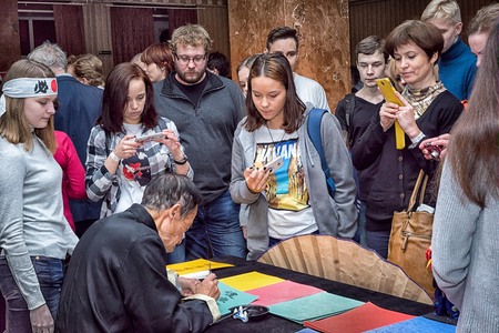 Moscow, Russia - 4 November, 2016: IV citywide action festival  "Night of the Arts". Calligrapher writes characters on colored paper in DK Nagorniy, visitors standing around and observing.のeditorial素材