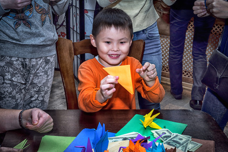 Moscow, Russia - 4 November, 2016: IV citywide action festival  "Night of the Arts". Boy making the origami crane in DK Nagorniy. Adults around to help him.のeditorial素材