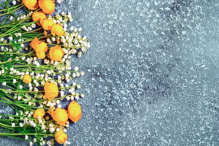 lily of the valley and globe flowers at the side of the cement background with copy spaceの写真素材