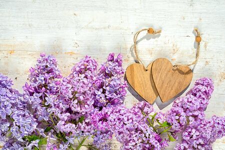 two wooden hearts with copy space for your text and bunch of lilac flowers on the wooden painted backgroundの写真素材
