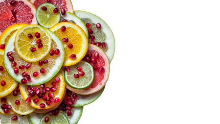 part of full citrus slices plate with pomegranate seeds isolated on white background with copy space at the sideの写真素材