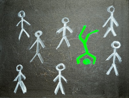 different and unique concept. green man standing on the head between usual white men, chalk drawing on the blackboard.の写真素材