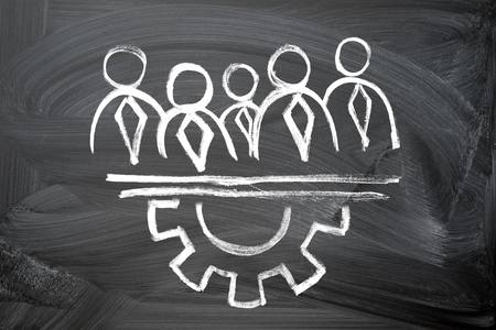 teamwork concept. chalk drawing on a blackboard of businessmen silhouettes and gear semicircleの写真素材
