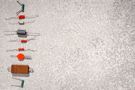 Old radio components in a vertical line as a bullets or frame for your text. Vintage high power resistors laying at the grey cement background, top view with copy space.の写真素材