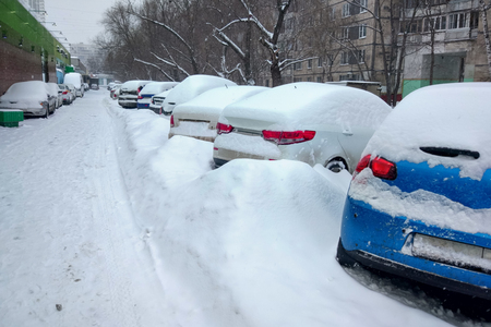 Snow covered cars in the parking lot. Urban scene, snowstorm. Snowdrifts  on the road and parking lot.の写真素材