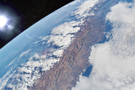 Cloud-covered Pacific coast of the South American nation of Chile contrasts with the Andes Mountain range and the cloud formations extending over Argentinaの写真素材