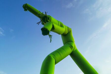 Inflatable dancing, flailing arms tube guy, against blue sky and cloudsの写真素材