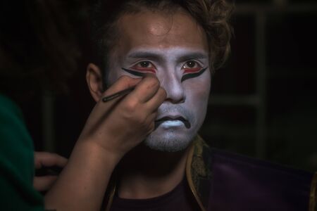 japanese taiko artist man puts makeup on face in the form of a demon mask, close up portraitの写真素材