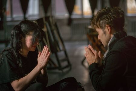 girl and guy are sitting on the floor in the room opposite each other with their hands clasped.