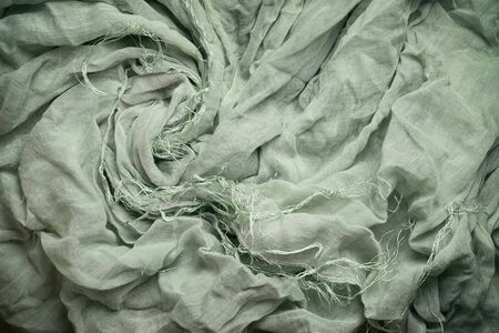 Green wavy cotton shawl with fringe, crumpled fabric. Background or elegant wallpaper design.の写真素材