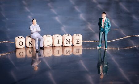 Miniature model of businessmen on a cubes online as text with letters, strung on a thread.