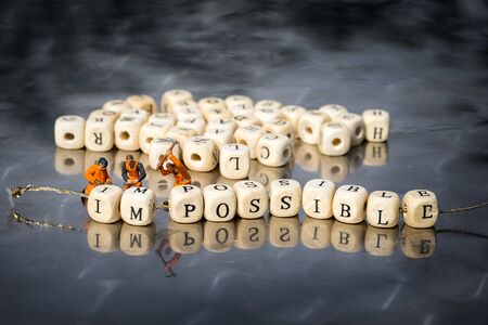 Miniature model of people remove wooden cubes with word impossible to possible.の写真素材